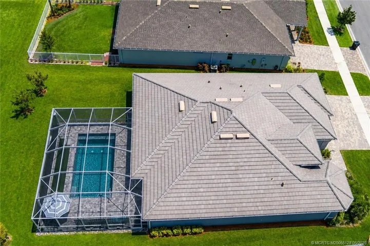 Overhead aerial view showcases the home’s impressive layout, expansive screened pool enclosure, and beautifully designed outdoor living spaces. Situated on a premium oversized lot with preserve views, this property offers exceptional privacy, generous outdoor space, and outstanding curb appeal in Del Webb at Tradition.