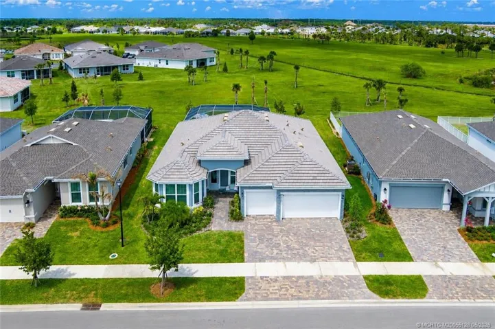 Exceptional aerial view showcases this beautifully positioned home with expansive preserve views and enhanced privacy in Del Webb at Tradition. Situated on a premium lot, the property features a screened pool, lush landscaping, paver driveway, and spacious outdoor living areas designed to capture the best of Florida living.