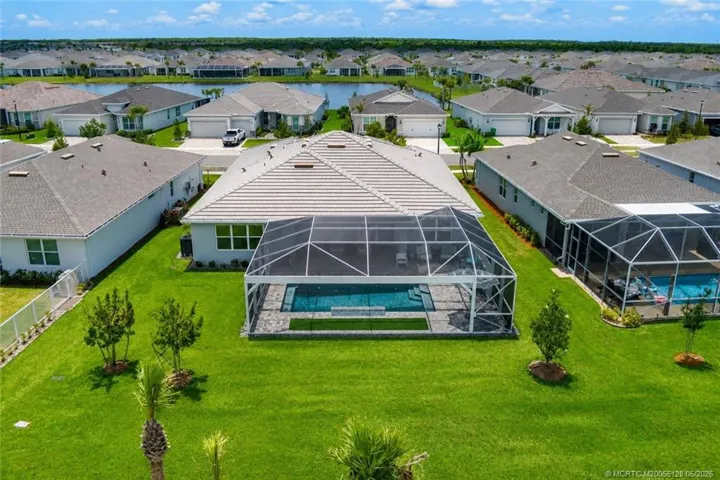 Aerial rear view highlights the home’s expansive screened pool enclosure, oversized lanai, and generous backyard with peaceful preserve views and no rear neighbors immediately behind. This premium lot offers exceptional privacy and plenty of outdoor space to enjoy the Florida lifestyle in Del Webb at Tradition.