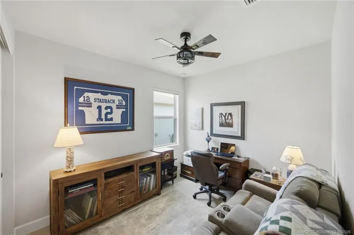 Versatile third bedroom is currently configured as a home office and media room, offering flexible space for work, hobbies, or overnight guests. Features include elegant tile flooring, abundant natural light, and a comfortable layout that easily adapts to your lifestyle needs.