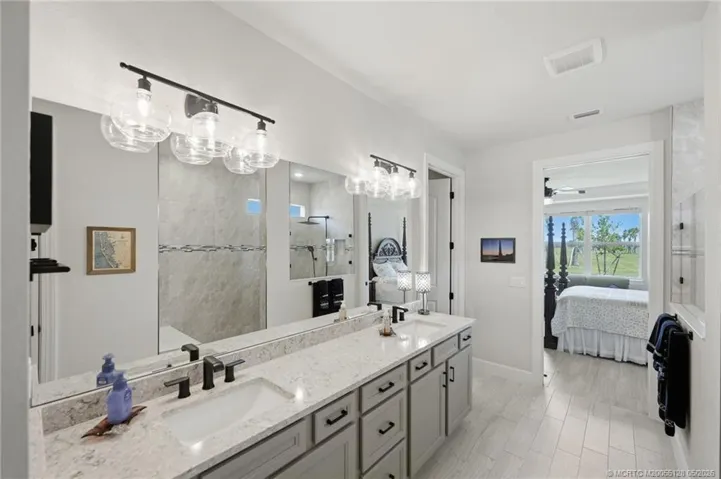 Luxurious primary bath features dual quartz vanities, upgraded cabinetry, designer lighting, and an oversized walk-in shower with elegant tile finishes and frameless glass enclosure. Spacious and beautifully appointed, this spa-inspired retreat offers comfort, style, and abundant storage.