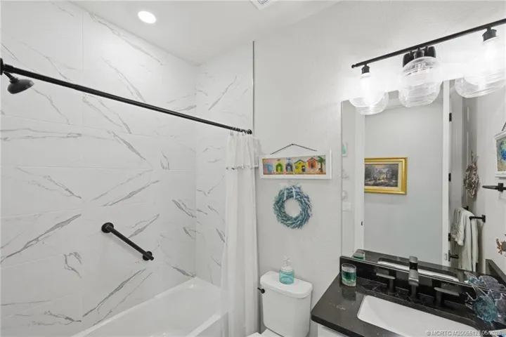 Stylishly upgraded full bath features designer tile surround, modern fixtures, upgraded vanity, and elegant finishes throughout. Thoughtfully designed to serve guests and secondary bedrooms with both comfort and contemporary style.