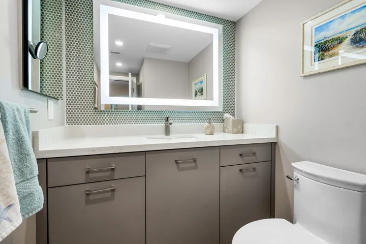 Spacious half bathroom with penny tile back splash, a light up mirror and a medicine cabinet for extra storage.