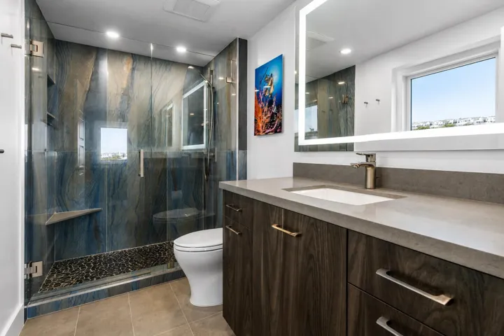 Luxurious guest suite bathroom with a marble walk in shower, light up mirror and custom cabinetry.