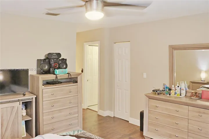 Room featuring wood-finish flooring, a neutral color palette, and a central ceiling fan with integrated lighting