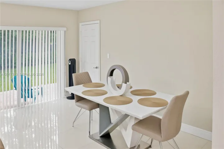Neutral-toned interior featuring high-gloss tile flooring, smooth wall finishes, and a sliding glass door with vertical blinds