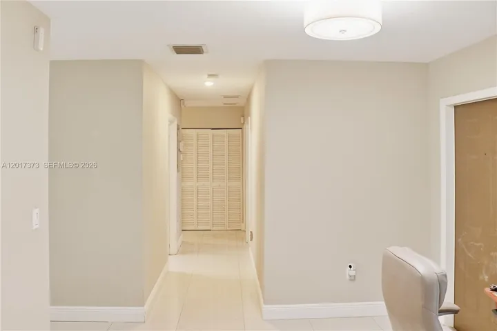 Neutral-toned interior space featuring tile flooring, a circular flush-mount ceiling light fixture, and bi-fold closet doors
