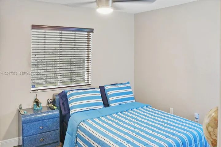 Neutral-toned walls featuring a brushed nickel ceiling fan and window with horizontal blinds