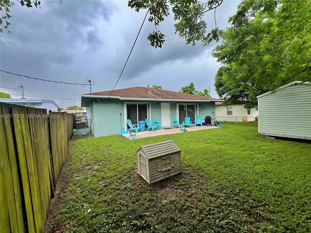 Rear exterior featuring a concrete patio, wood privacy fencing, and a detached storage structure