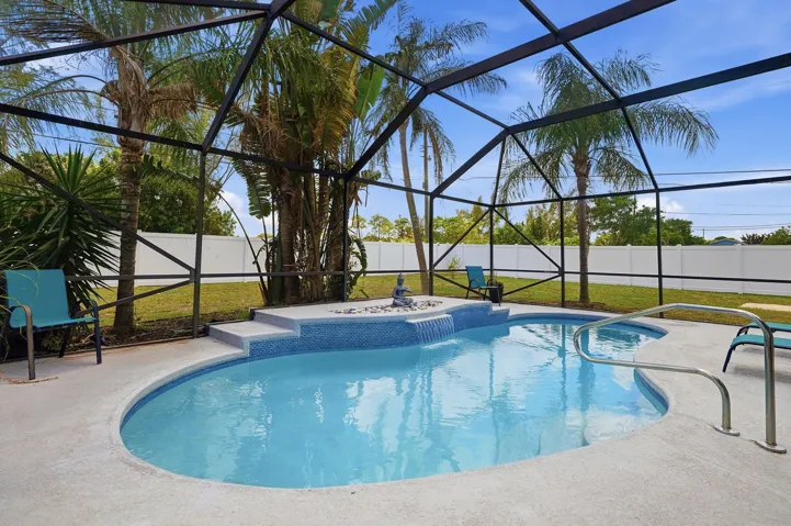 Bright blue pool with waterfall and screened enclosure
