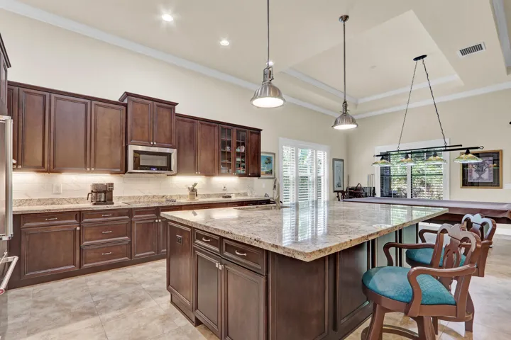 Granite countertops, tiled backsplash, large central island with additional storage