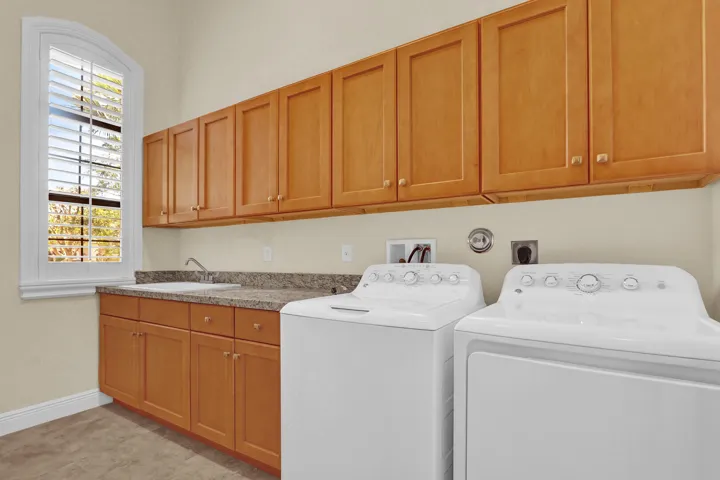 large laundryroom off the garage with sink and loads of cabinets for extra storage