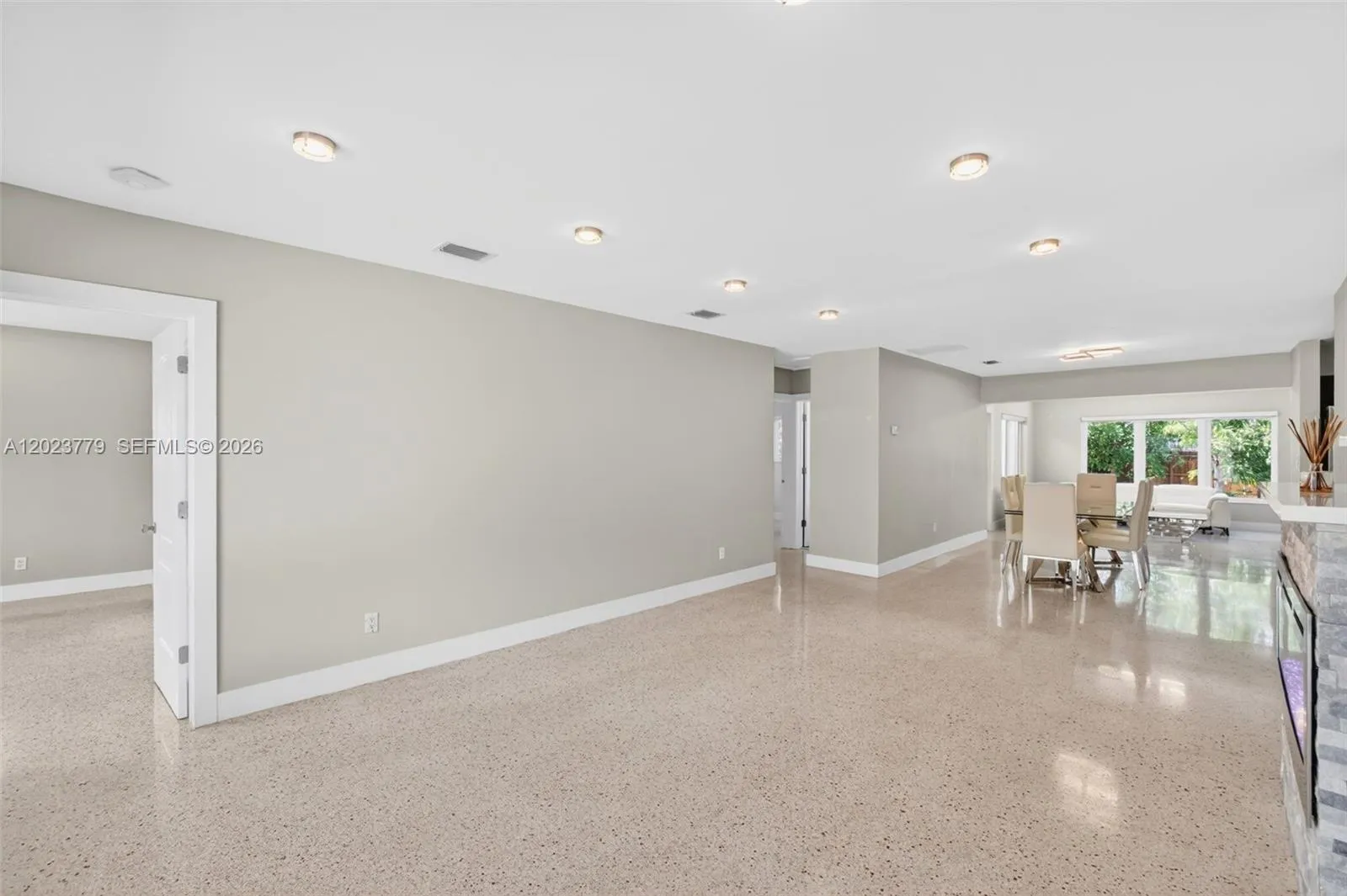Stacked Stone Electric Fireplace with color changing light, lots of high hat lighting, beautiful restored polished terrazzo flooring. Flat ceilings and neutral beautiful paint. Door to left leads to primary bedroom