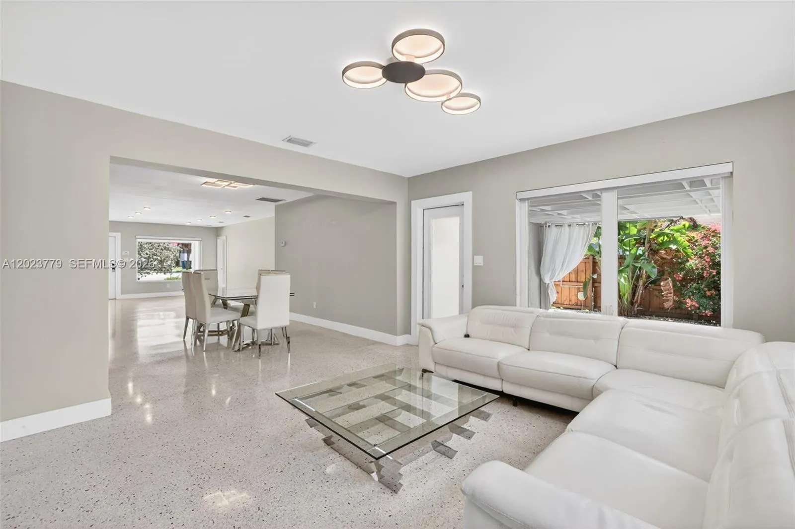 Inviting Family Room with Stacked Stone accent wall, original and restored and polished terrazzo floors and large impact windows overlooking the private tropical backyard