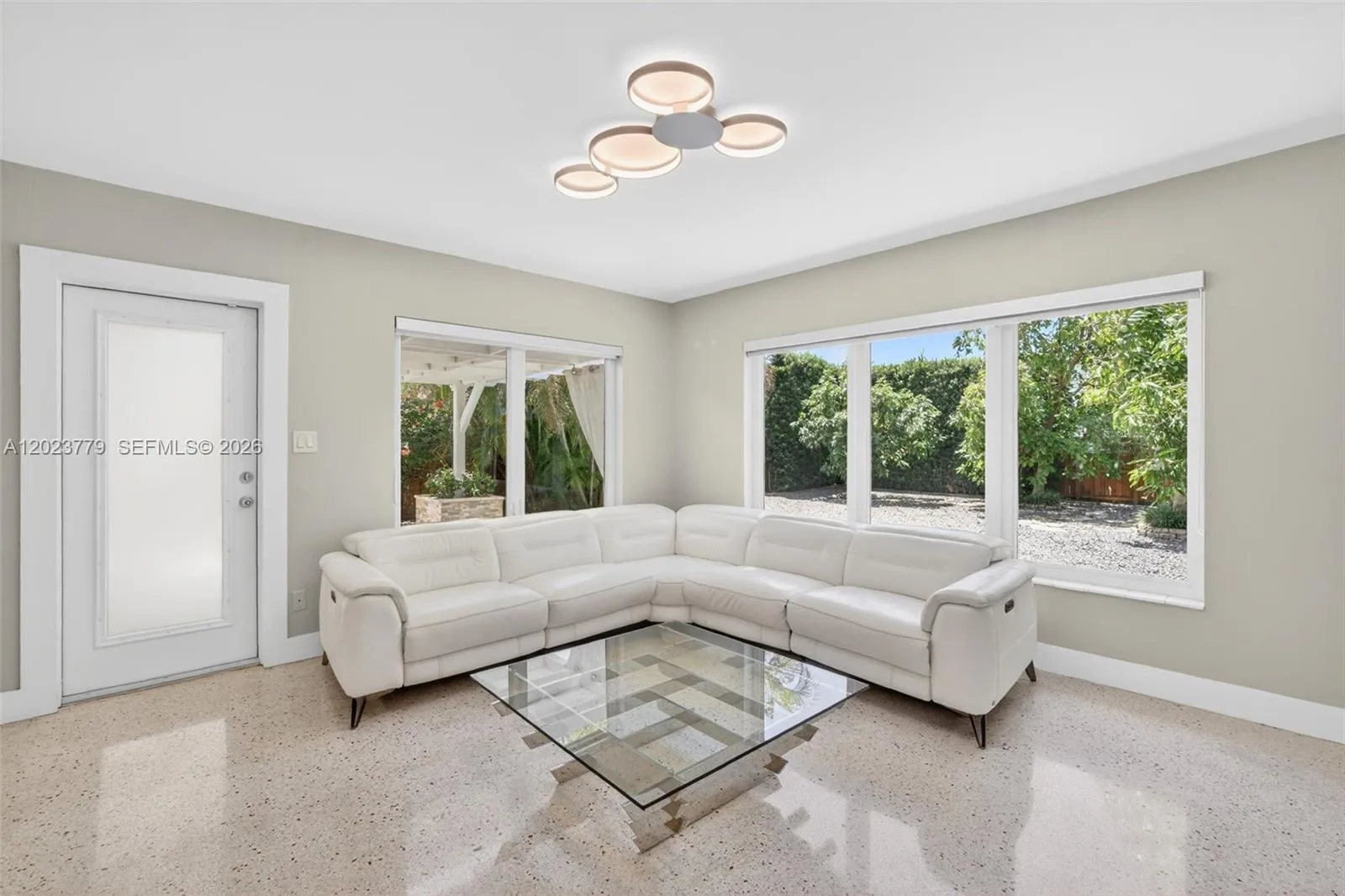 Inviting Family Room with Stacked Stone accent wall, original and restored and polished terrazzo floors and large impact windows overlooking the private tropical backyard