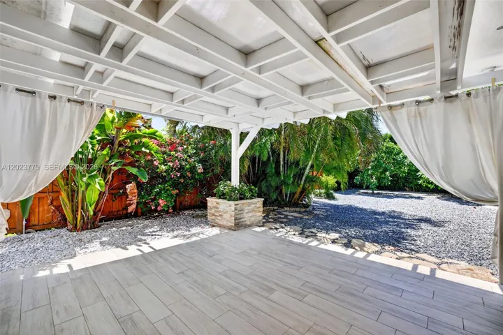 Covered patio overlooking backyard, tiled floor and stacked stone planter