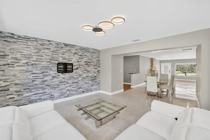 Inviting Family Room with Stacked Stone accent wall, original and restored and polished terrazzo floors and large impact windows overlooking the private tropical backyard