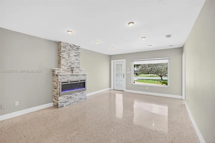 Stacked Stone Electric Fireplace with color changing light, lots of high hat lighting, beautiful restored polished terrazzo flooring. Flat ceilings and neutral beautiful paint
