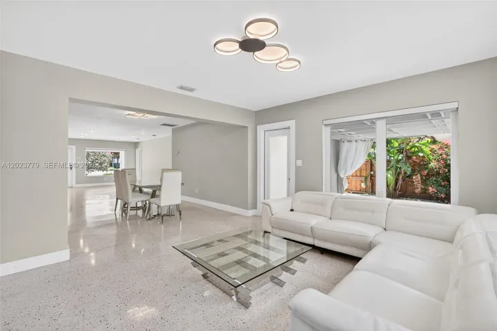 Inviting Family Room with Stacked Stone accent wall, original and restored and polished terrazzo floors and large impact windows overlooking the private tropical backyard