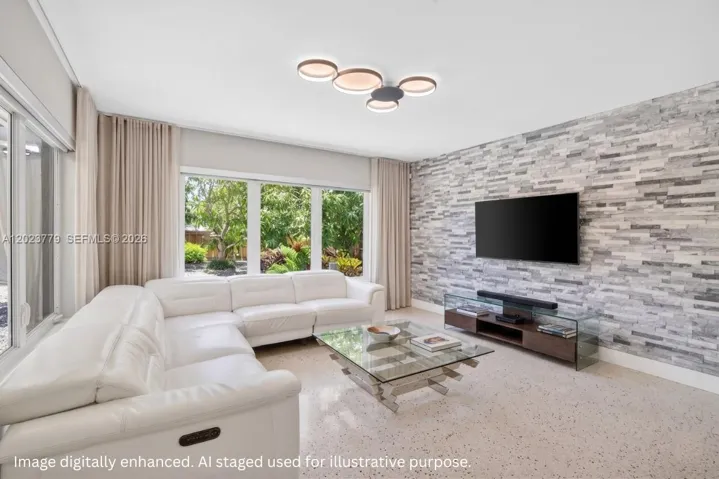 Inviting Family Room with Stacked Stone accent wall, original and restored and polished terrazzo floors and large impact windows overlooking the private tropical backyard. Virtually staged