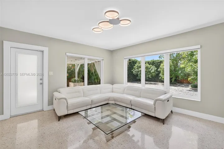 Inviting Family Room with Stacked Stone accent wall, original and restored and polished terrazzo floors and large impact windows overlooking the private tropical backyard