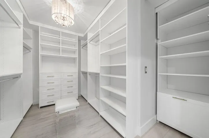 Primary walk-in closet with convenient shelves, drawers