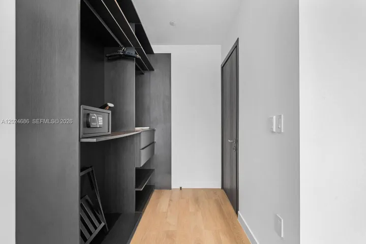 Custom walk-in closet featuring dark wood-finish cabinetry, built-in shelving, integrated drawers, and wood-finish flooring
