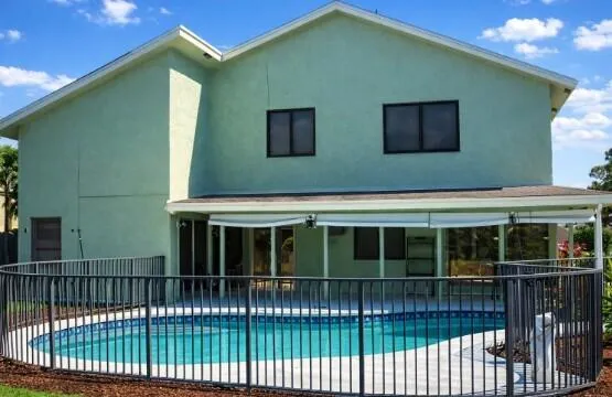 Expansive Backyard Oasis with patio and fenced pool.