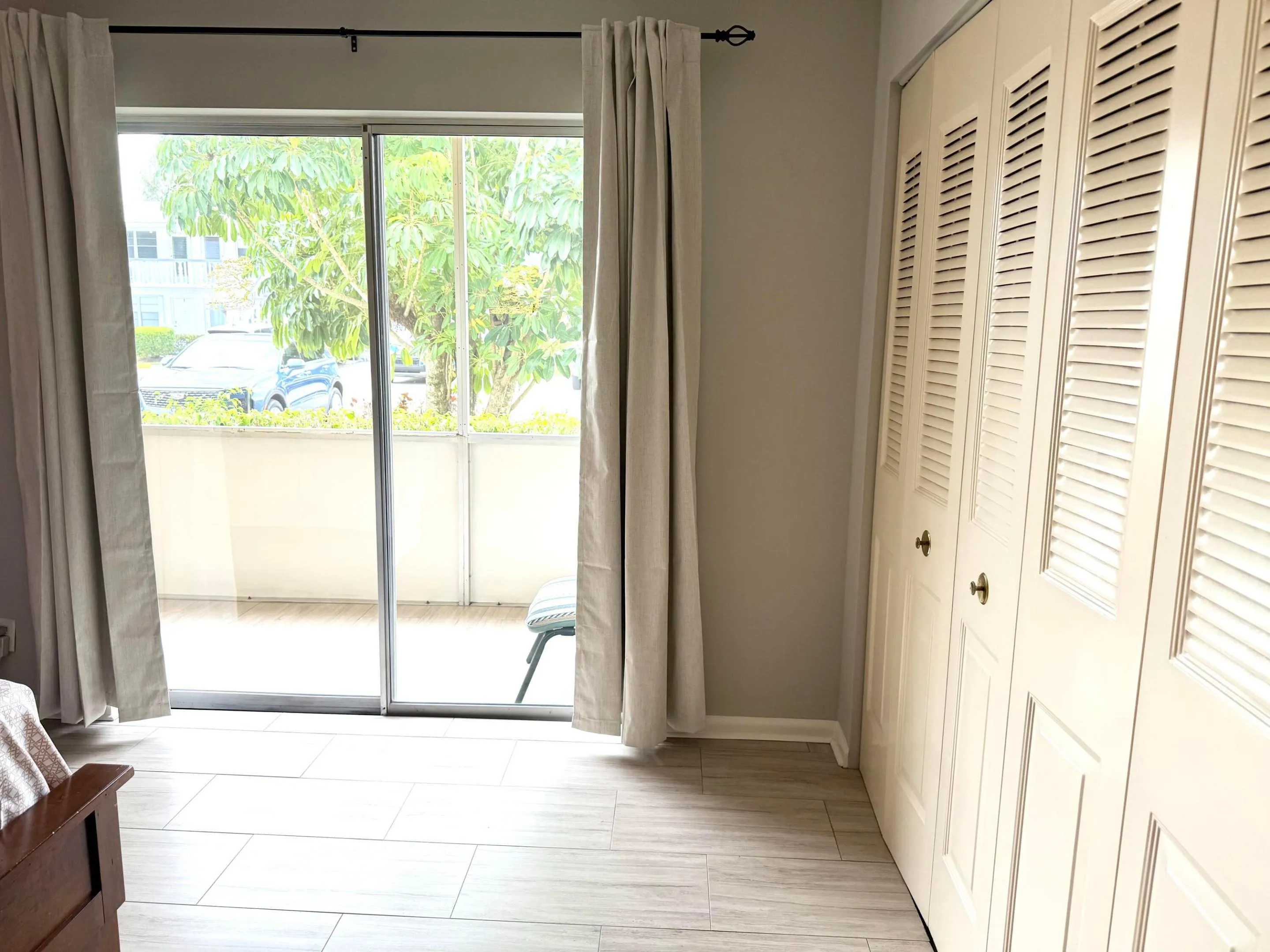 Spacious bedroom looking out to enclosed sreen- in porch, also includes beautiful curtain rod and brand new sun blocking privacy curtains.