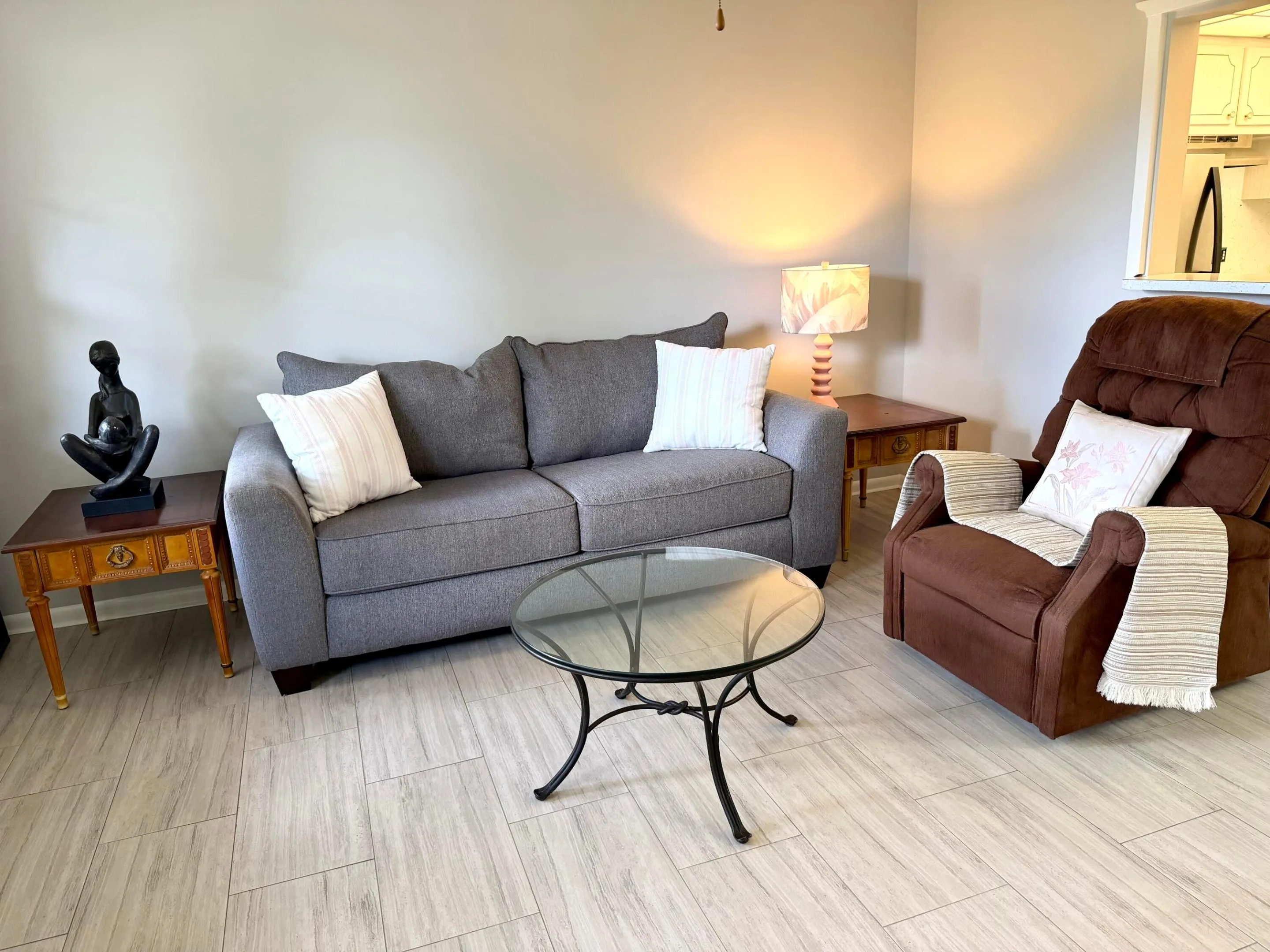 Living room area with sofa, recliner and wrought iron coffer table.