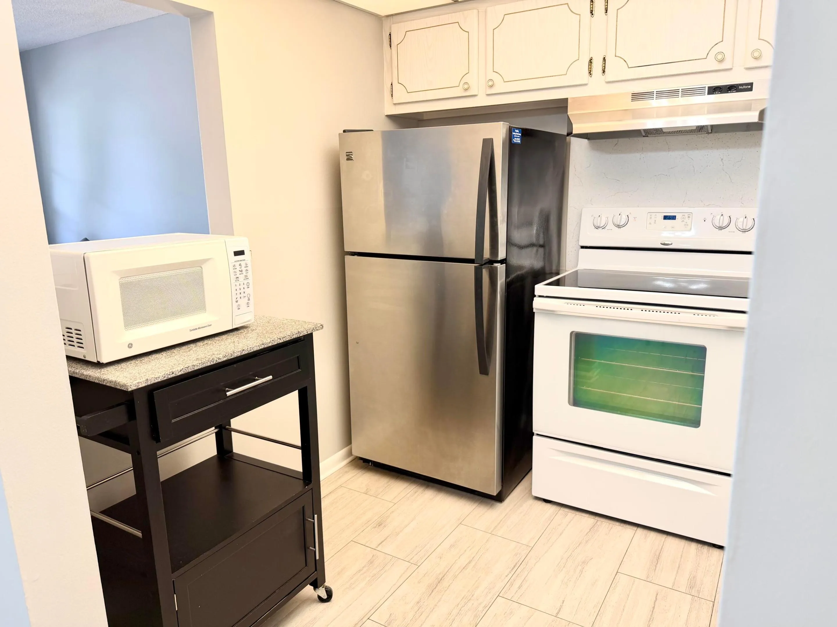 Kitchen with newer stainless steel refrigerator and stainless steel kitchen hood.