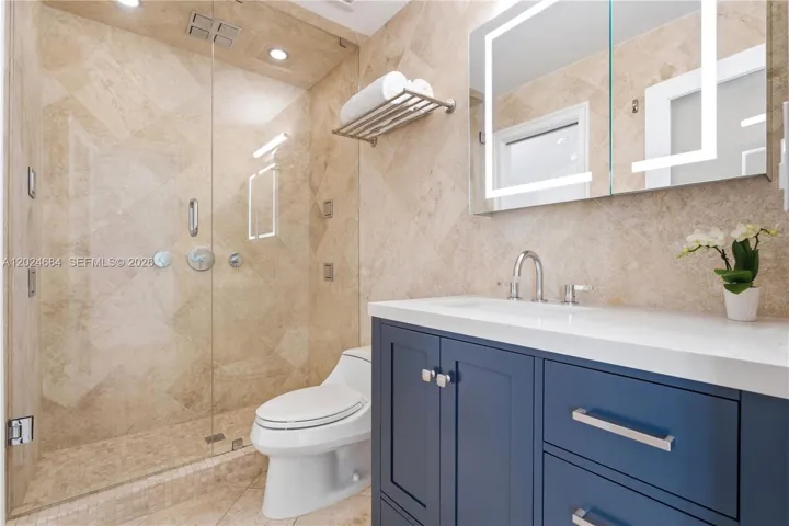 Shower with 8 adjustable shower heads - 4 ceiling-mounted, 4 body sprays. Using only the body sprays a person can shower without wetting their hair. Medicine cabinet with adjustable front facing light. New vanity with ample storage