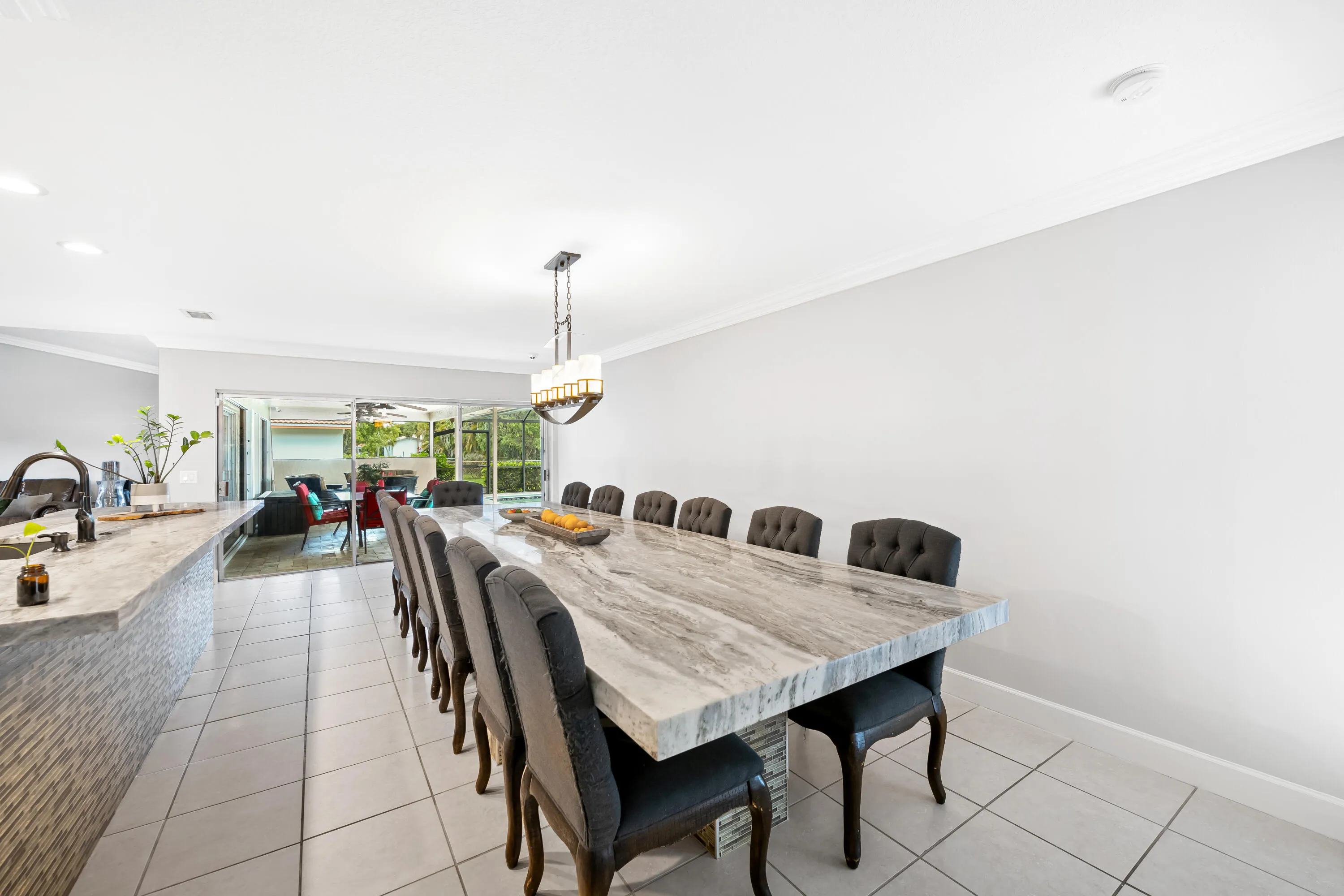 Large dining room with view of back patio with pavers and saltwater pool