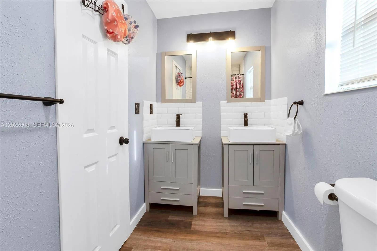 Featuring dual vanities, modern fixtures, and a beautifully tiled shower/tub combination.