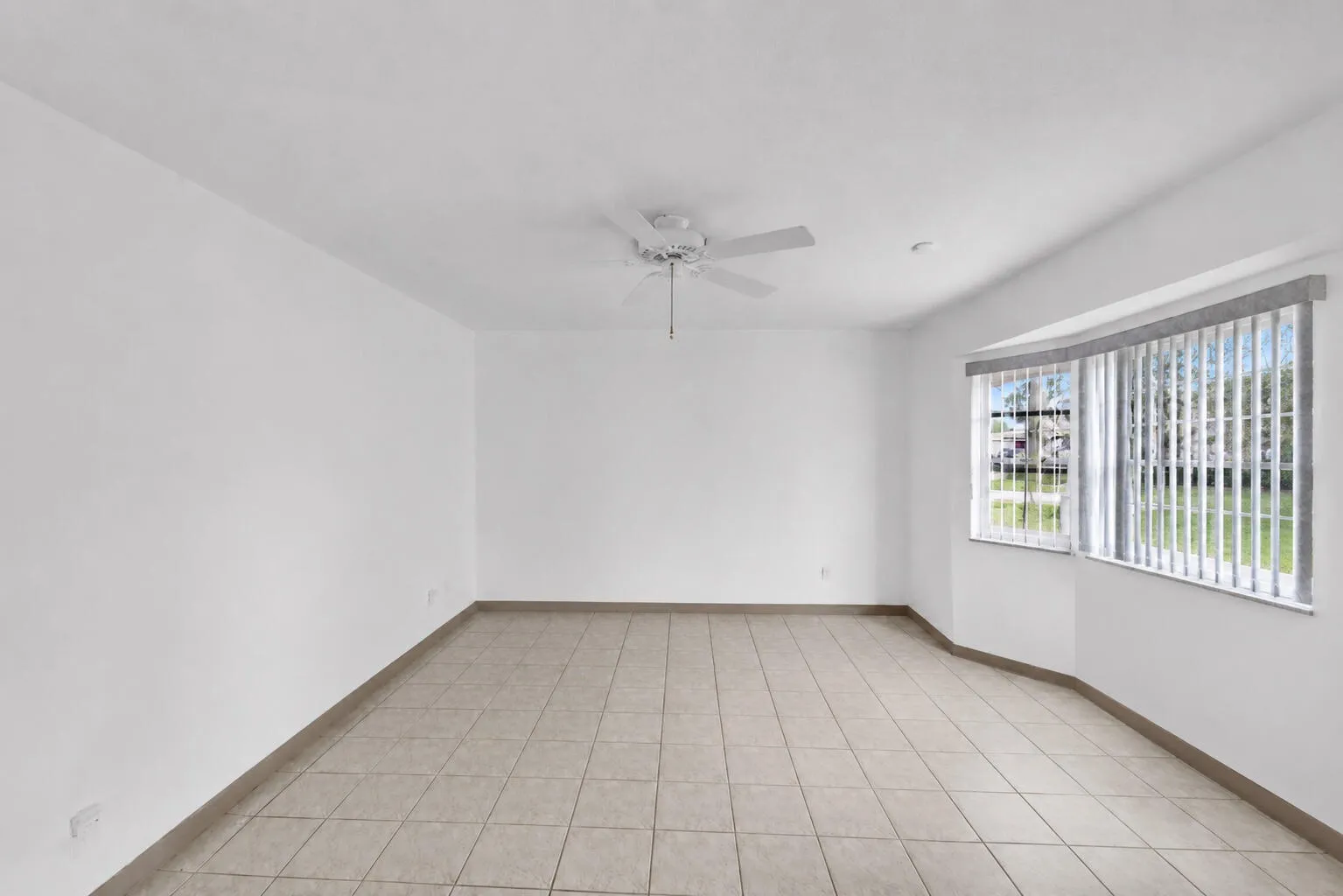 Photoshop - Spacious Living Room with Neutral Tile and Bay Window.