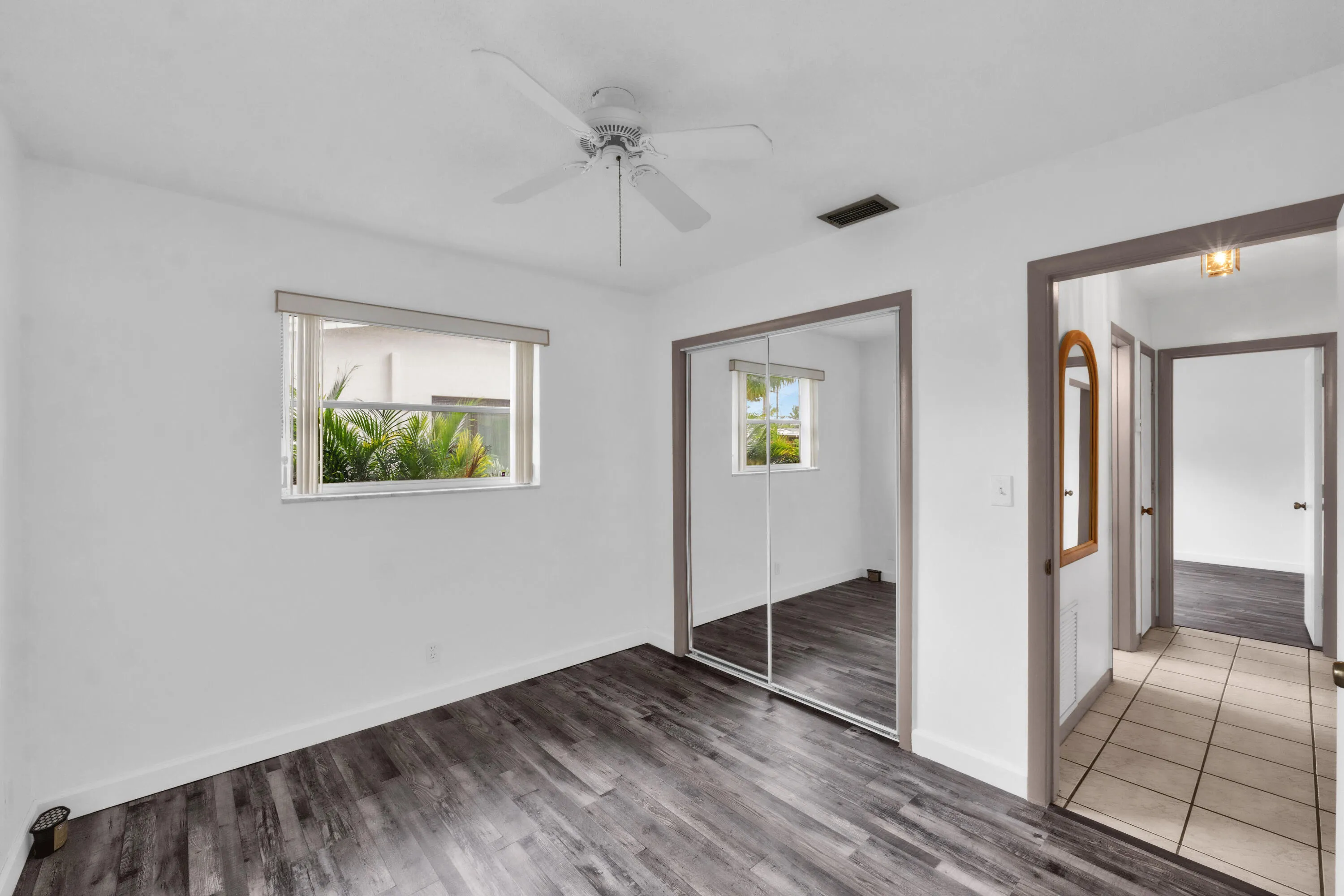 Front Bedroom with Luxury Vinyl Plank Flooring. Tiled Hallway leads to Second Bathroom