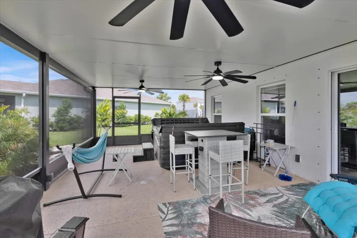 Large screened-in area with epoxy floor, ceiling fans, and hot tub