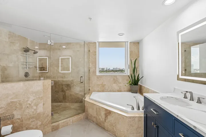 Frameless glass doors lead into the spacious shower, Roman Tub, and double vanity with LED lighted mirrors.