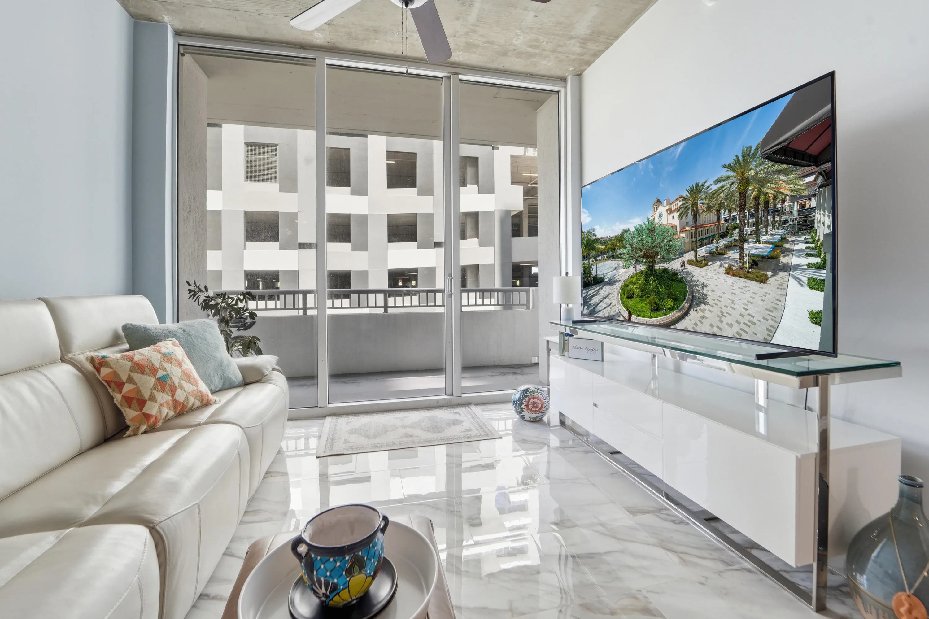 Spacious living area with loft-inspired architecture, floor to ceiling windows, and exposed concrete ceilings