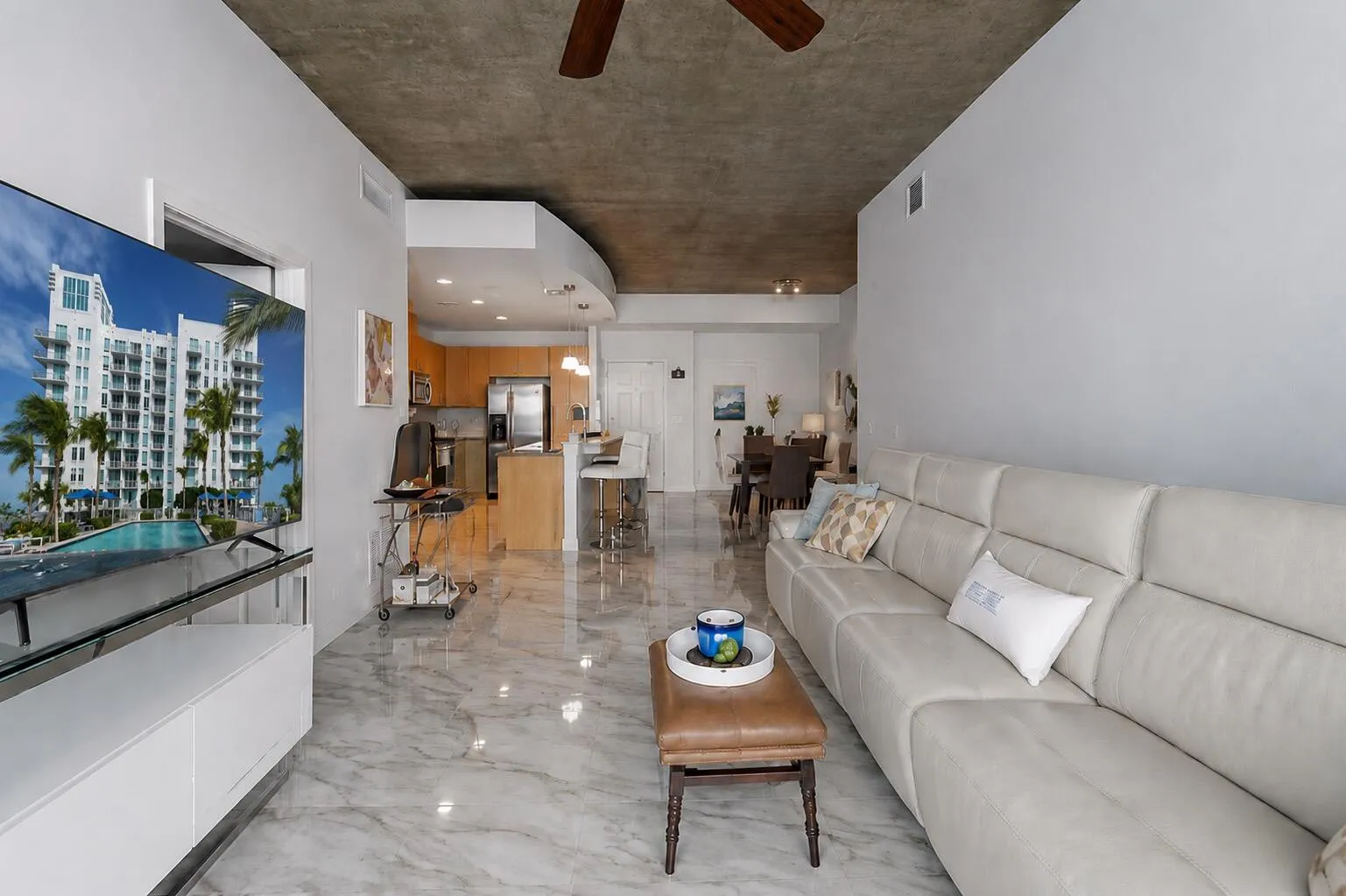 Spacious living area with loft-inspired architecture, floor to ceiling windows, and exposed concrete ceilings