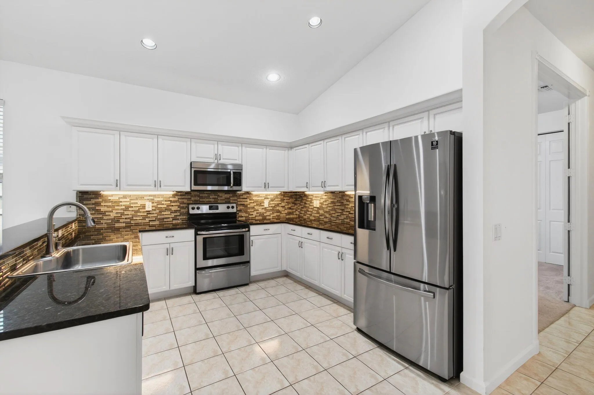 Updated kitchen has glass mosaic tile backsplash