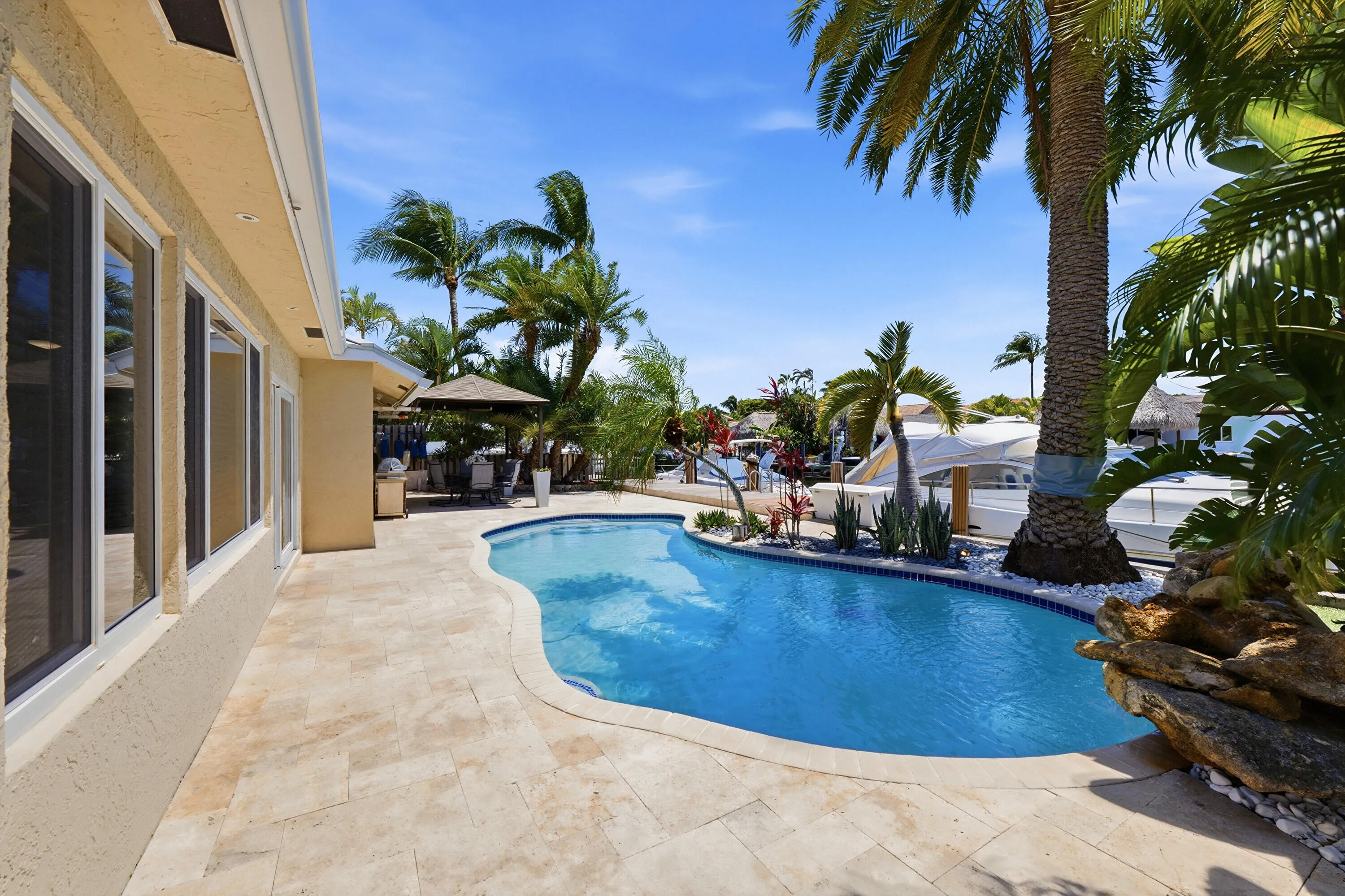 Your Waterfront Freeform Pool with Rock Waterfall adds to the Serene Waterfront Lifestyle & is Surrounded by Beautiful Landscape.
