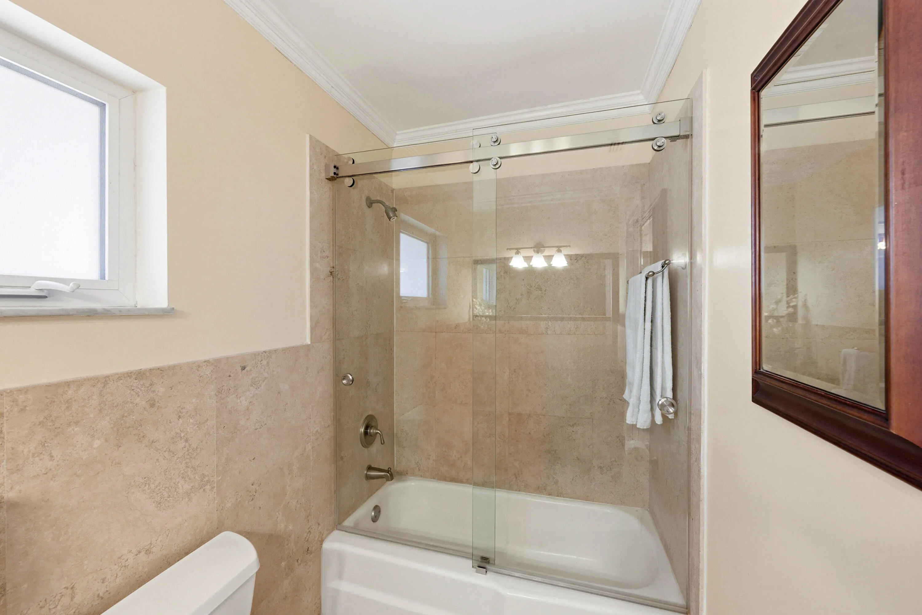 Primary En-Suite Bathoom with Custom Cabinet, Granite Countertop, Bathtub & Shower Combination with Glass Enclosure all behing a Frosted Glass Bathroom Pocket Door.