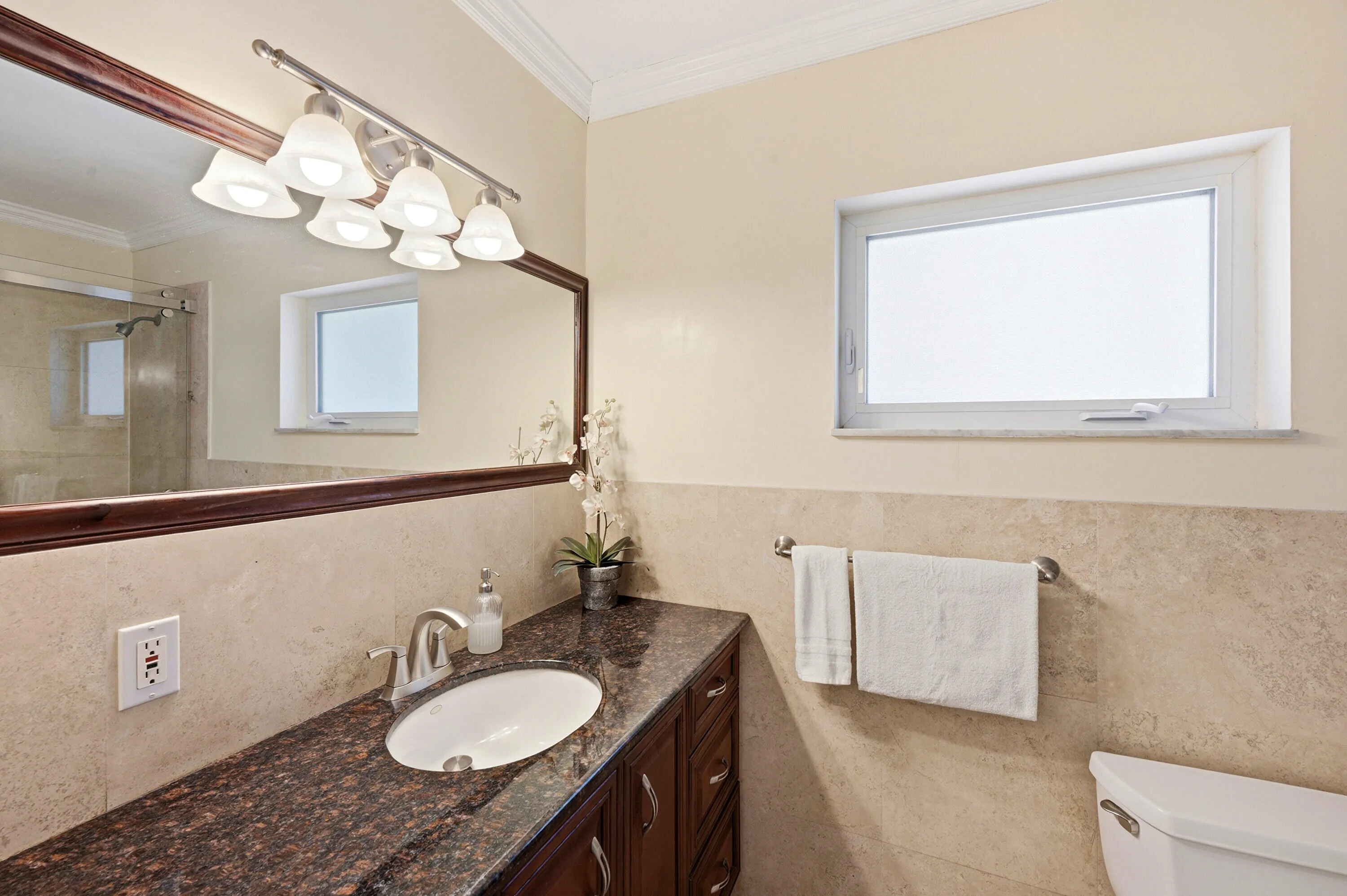 Primary En-Suite Bathoom with Custom Cabinet, Granite Countertop, Bathtub & Shower Combination with Glass Enclosure all behing a Frosted Glass Bathroom Pocket Door.
