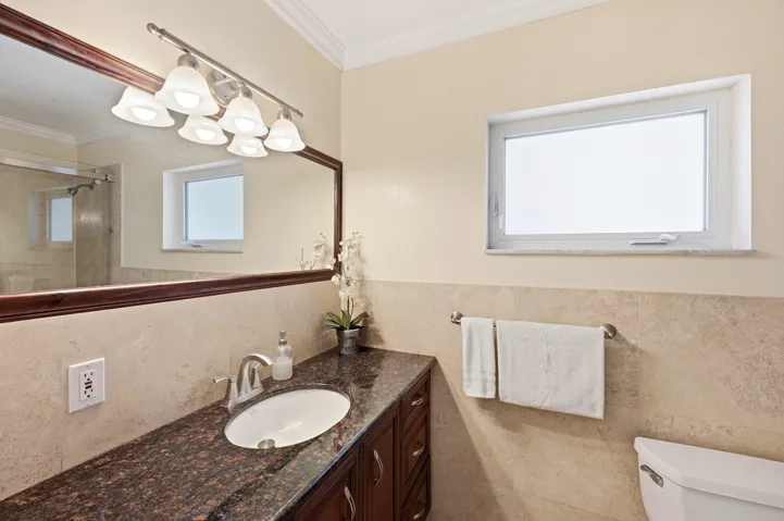 Primary En-Suite Bathoom with Custom Cabinet, Granite Countertop, Bathtub & Shower Combination with Glass Enclosure all behing a Frosted Glass Bathroom Pocket Door.