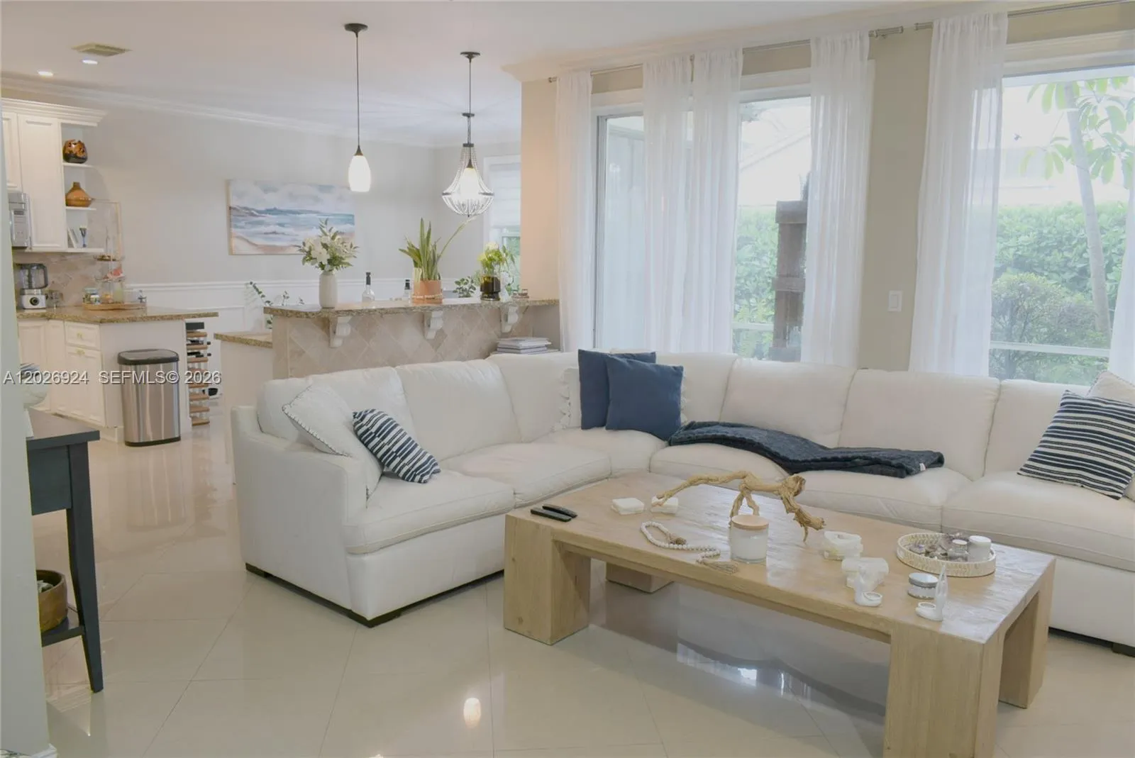 Open integrated living and kitchen layout featuring a bright seating area, coastal décor accents, and a well-connected space ideal for everyday living and entertaining.