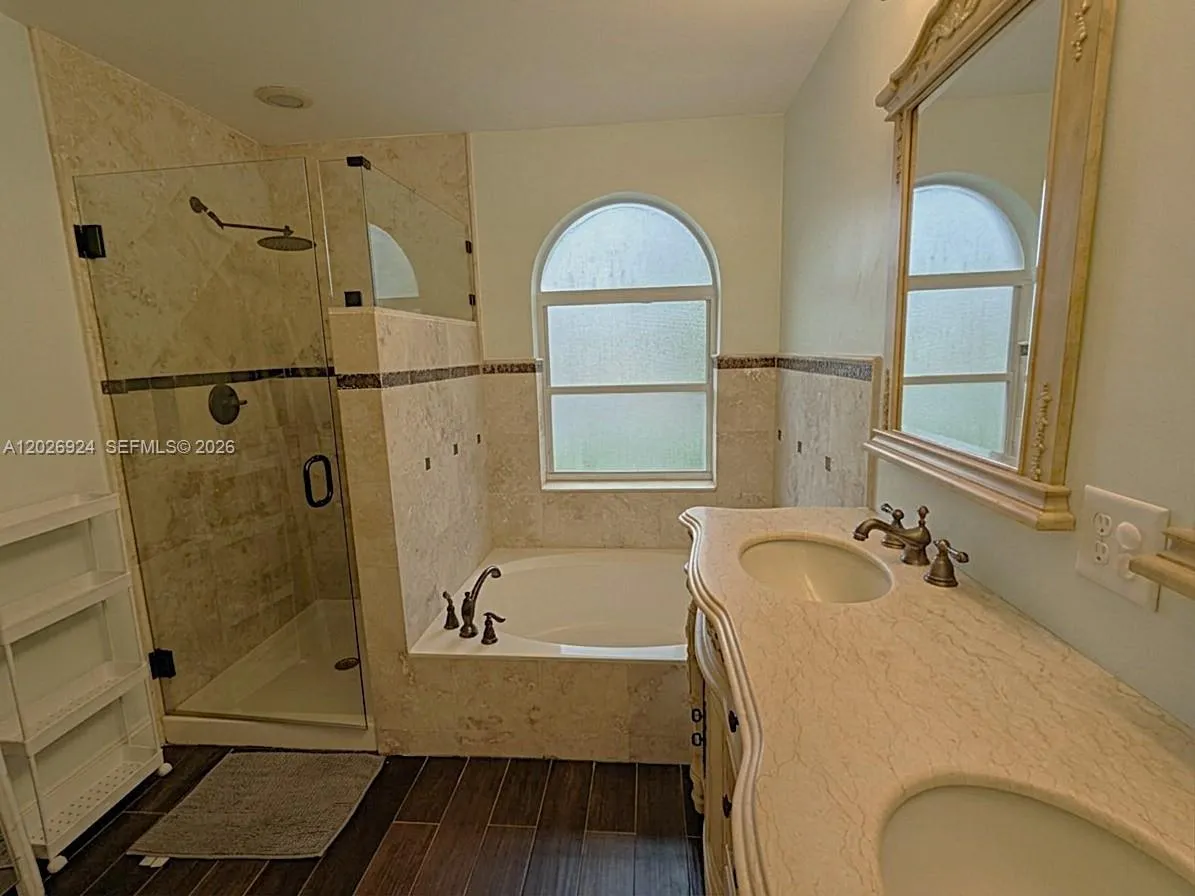 Charming master bathroom with double sink vanity, bathtub and glass door shower.