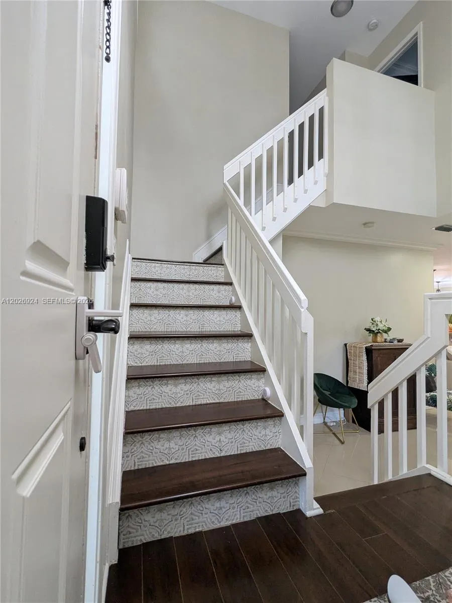Inviting entry area featuring a modern staircase with patterned risers, wood steps, and clean white railings, creating a stylish transition between levels.