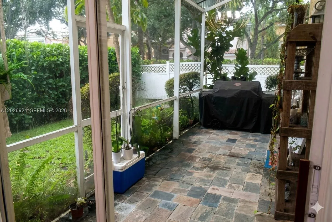 Lush landscape view from the screened-in patio. Stone tile flooring, and room for a covered grill area, offering a comfortable outdoor space protected from the elements.
