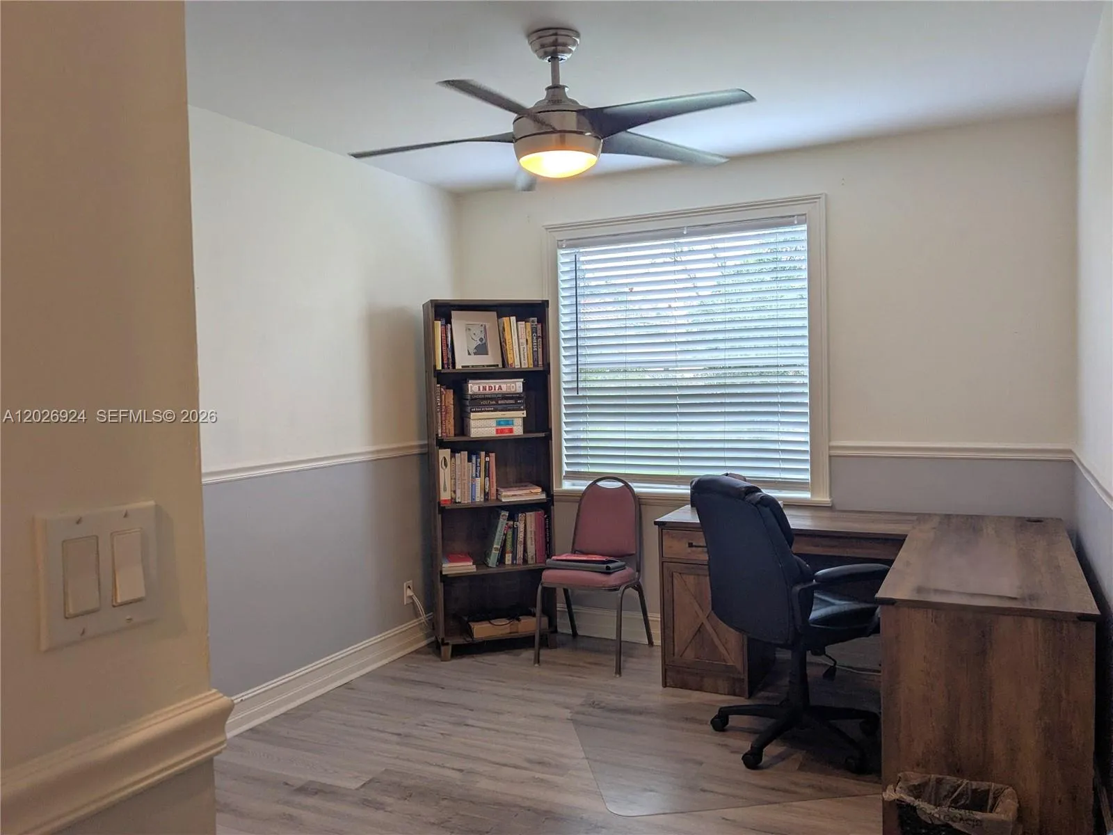 Third bedroom currently set up as a home office, featuring wood-style flooring, closet, natural light, and a ceiling fan, offering a versatile space for work or living.